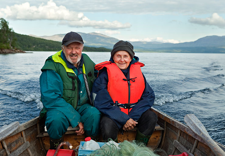 Bilde av et eldre par med flyteplagg i båt