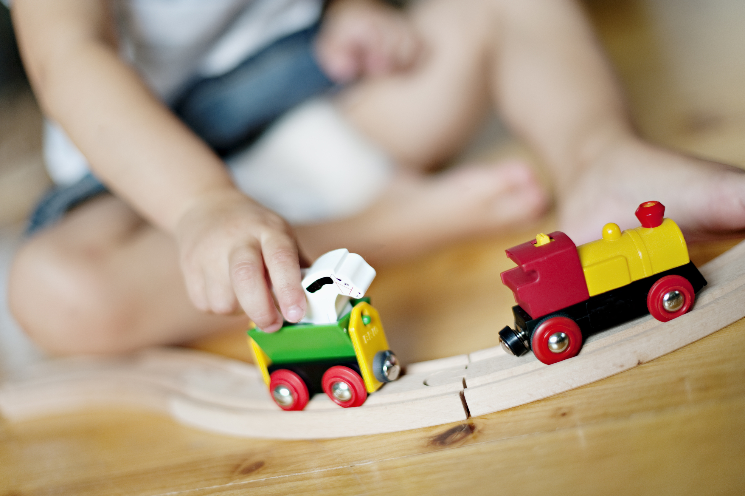 Barnehender som leker med tog på togbane