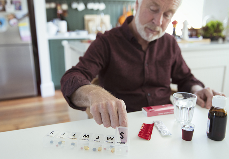 Elderly man putting pills in box