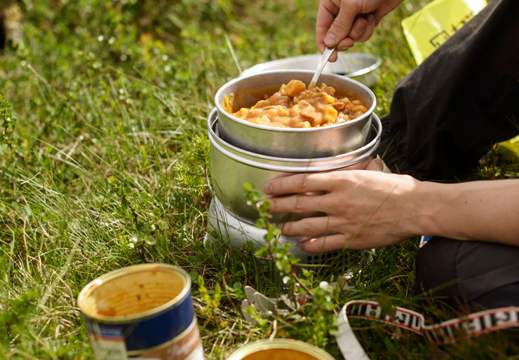 Hands handling food over camp stove